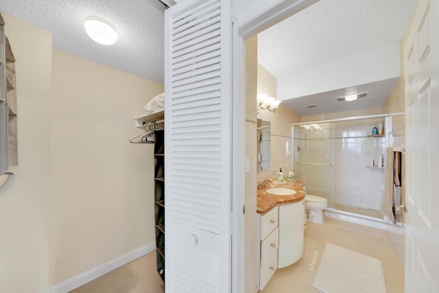 bathroom featuring vanity, a textured ceiling, a shower with shower door, tile patterned floors, and toilet