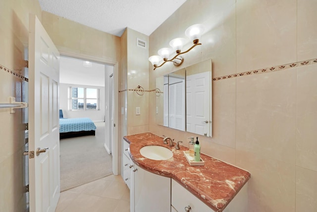 bathroom featuring vanity, tile walls, tile patterned floors, and a textured ceiling