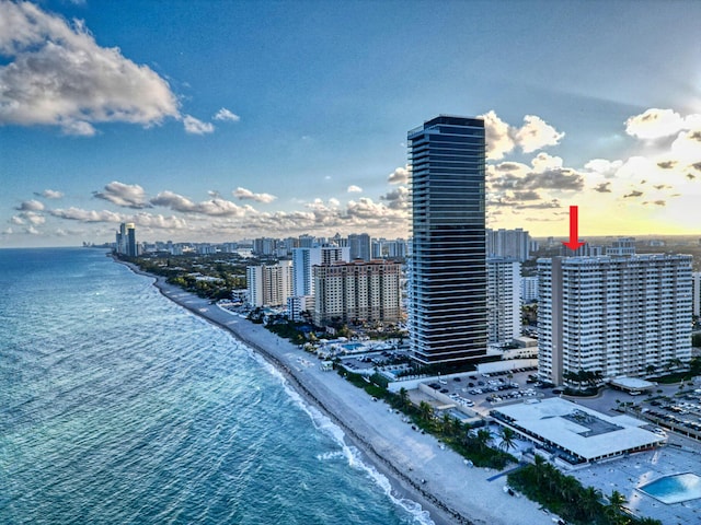 aerial view at dusk featuring a water view and a beach view