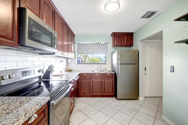 kitchen featuring stainless steel appliances, tasteful backsplash, light stone countertops, and sink