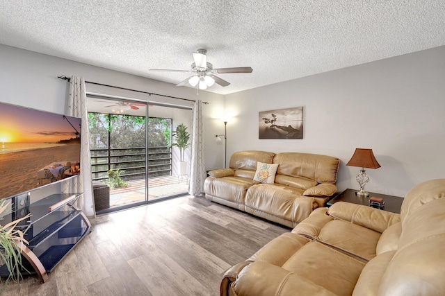 living room with hardwood / wood-style flooring, ceiling fan, and a textured ceiling