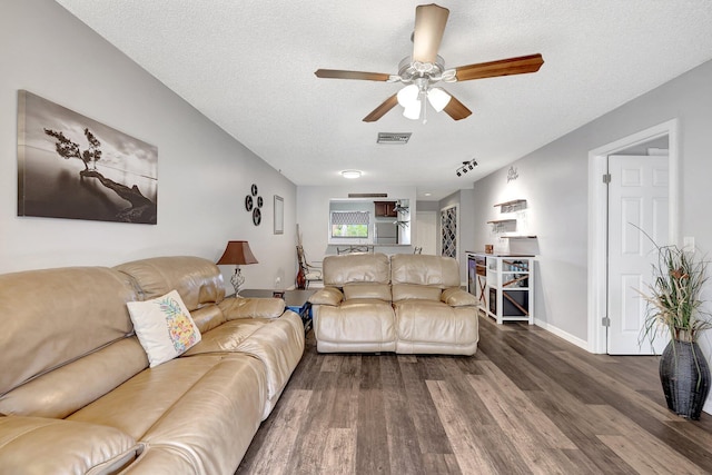 living room featuring ceiling fan, dark hardwood / wood-style floors, and a textured ceiling