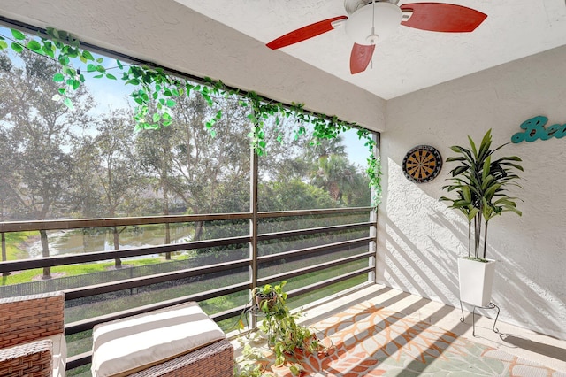 sunroom featuring a water view and ceiling fan