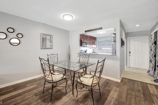 dining space with sink, dark hardwood / wood-style floors, and a textured ceiling