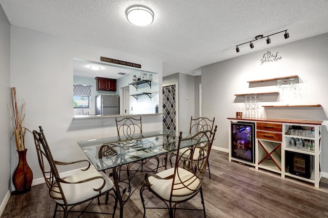 dining space with dark wood-type flooring, beverage cooler, indoor wet bar, and a textured ceiling