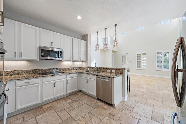 kitchen featuring appliances with stainless steel finishes, decorative light fixtures, and white cabinets