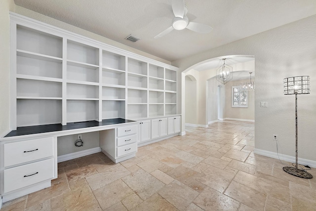 unfurnished office featuring ceiling fan, built in desk, and a textured ceiling