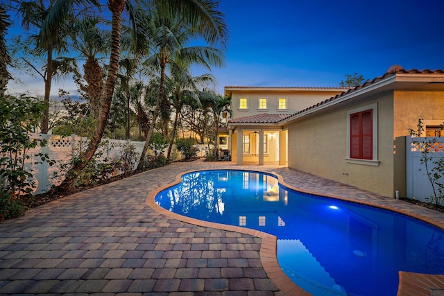 pool at dusk with a patio