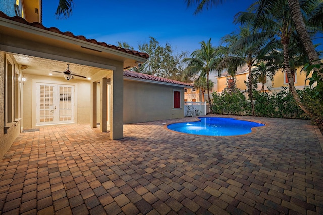 pool at dusk with ceiling fan, a patio, and french doors