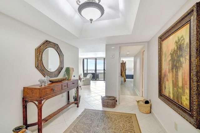 hallway featuring a raised ceiling and light tile patterned flooring