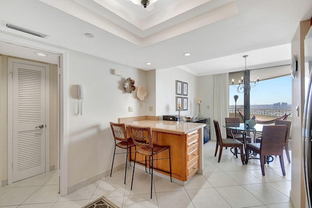 kitchen with hanging light fixtures, a kitchen bar, light tile patterned flooring, kitchen peninsula, and a chandelier