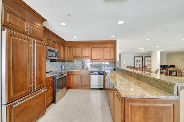 5080 N Ocean Dr Unit 20C, Riviera Beach, FL 33404 - kitchen with appliances with stainless steel finishes, a peninsula, light stone countertops, tasteful backsplash, and a sink
