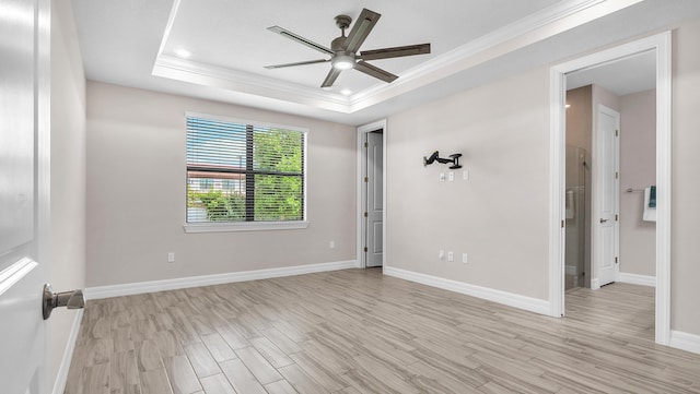 unfurnished room featuring ornamental molding, light hardwood / wood-style flooring, ceiling fan, and a tray ceiling