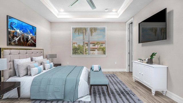 bedroom with crown molding, a tray ceiling, and light wood-type flooring