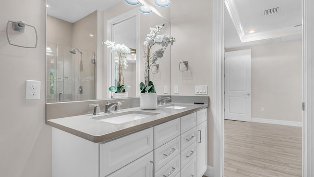 bathroom with hardwood / wood-style floors, vanity, walk in shower, a tray ceiling, and crown molding