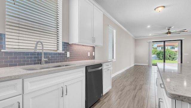 kitchen featuring white cabinetry, dishwasher, sink, ornamental molding, and light stone counters