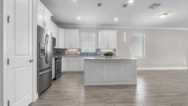 kitchen with appliances with stainless steel finishes, tasteful backsplash, white cabinets, a kitchen island, and decorative light fixtures