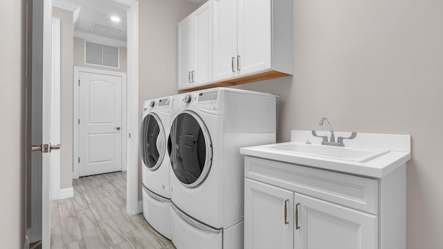 laundry room with sink, light hardwood / wood-style floors, cabinets, and washing machine and clothes dryer