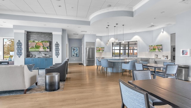 dining area with crown molding, a tray ceiling, and light hardwood / wood-style flooring