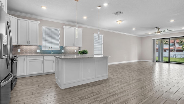 kitchen with white cabinetry, stainless steel fridge with ice dispenser, light stone counters, and decorative backsplash