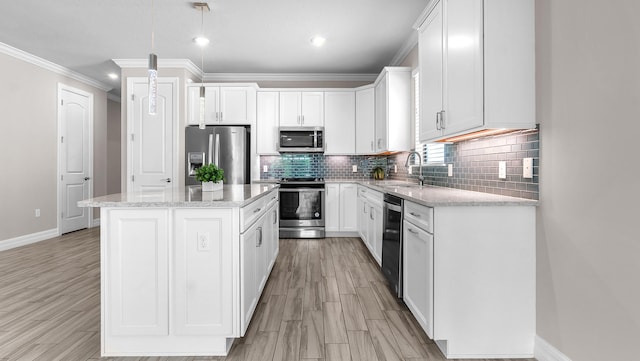 kitchen featuring a kitchen island, appliances with stainless steel finishes, white cabinetry, sink, and hanging light fixtures