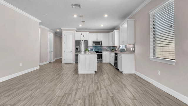 kitchen featuring tasteful backsplash, a center island, white cabinets, and appliances with stainless steel finishes