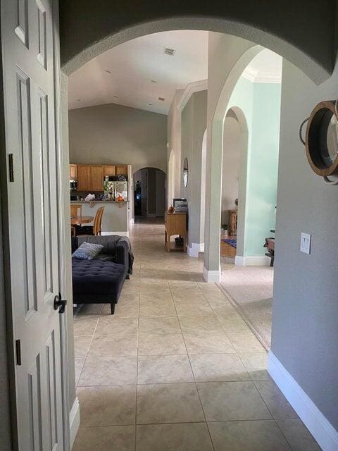 hall with high vaulted ceiling and light tile patterned floors