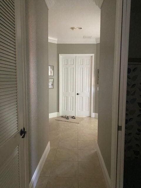 hall featuring crown molding and light tile patterned floors