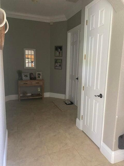 hallway featuring crown molding and light tile patterned floors