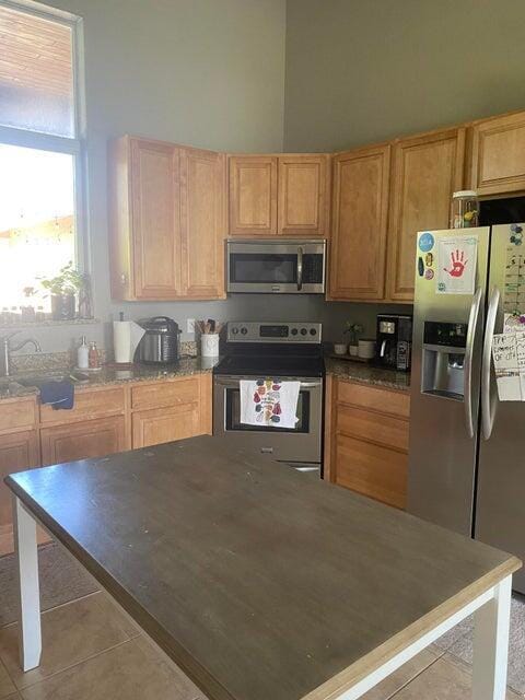 kitchen featuring sink, light tile patterned flooring, stainless steel appliances, and a high ceiling