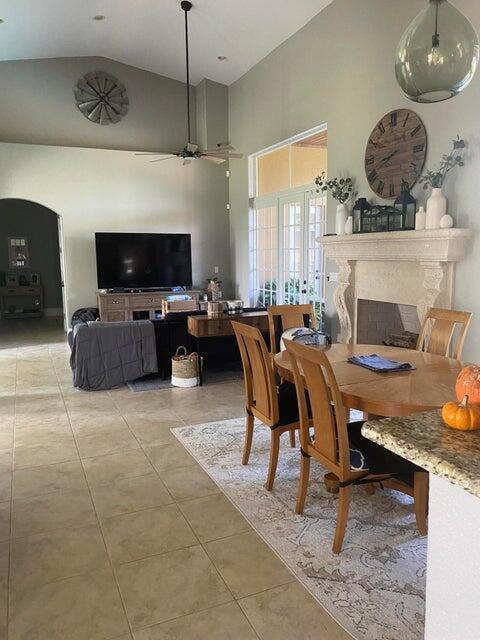 tiled dining space featuring ceiling fan and high vaulted ceiling