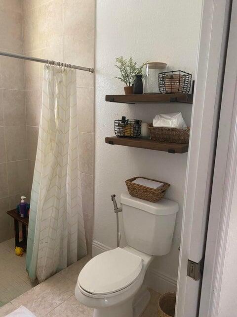 bathroom featuring tile patterned flooring, toilet, and a shower with shower curtain