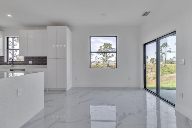 kitchen featuring white cabinets, marble finish floor, a healthy amount of sunlight, and modern cabinets