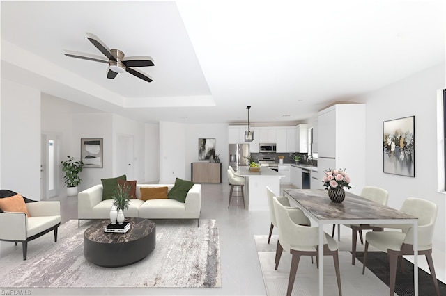 living room with a raised ceiling and a ceiling fan