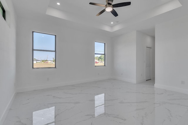 unfurnished room with a tray ceiling, recessed lighting, and baseboards