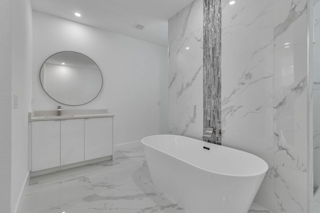 full bathroom with visible vents, marble finish floor, a freestanding bath, vanity, and stone wall