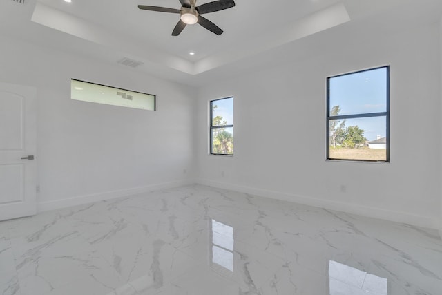 empty room with baseboards, visible vents, marble finish floor, a tray ceiling, and recessed lighting