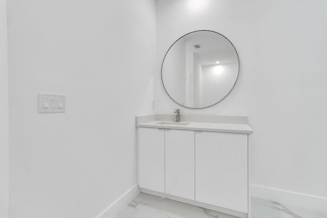 bathroom with marble finish floor, vanity, and baseboards