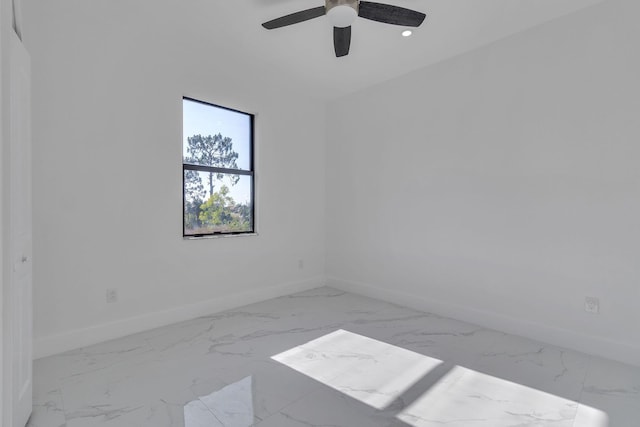 unfurnished room with marble finish floor, baseboards, and a ceiling fan