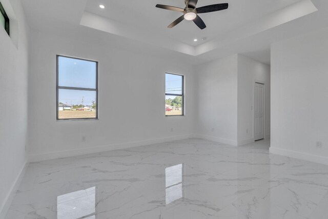 unfurnished room featuring recessed lighting, a raised ceiling, and baseboards