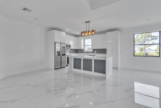 kitchen featuring stainless steel appliances, visible vents, hanging light fixtures, light countertops, and decorative backsplash