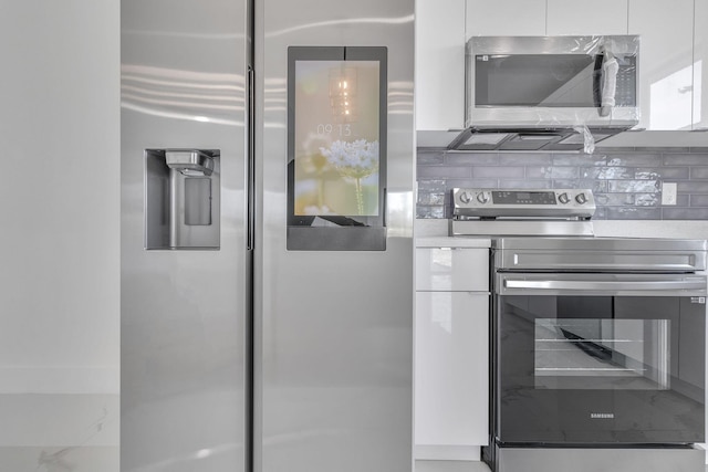 kitchen featuring stainless steel appliances, modern cabinets, white cabinets, and tasteful backsplash