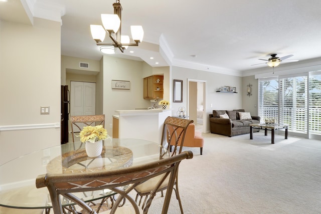 carpeted dining area with crown molding and ceiling fan with notable chandelier