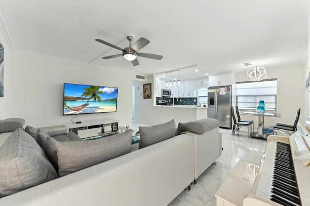 living room featuring crown molding, sink, and ceiling fan with notable chandelier