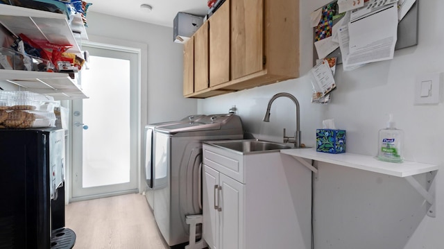 washroom featuring cabinets, washing machine and dryer, sink, and light wood-type flooring