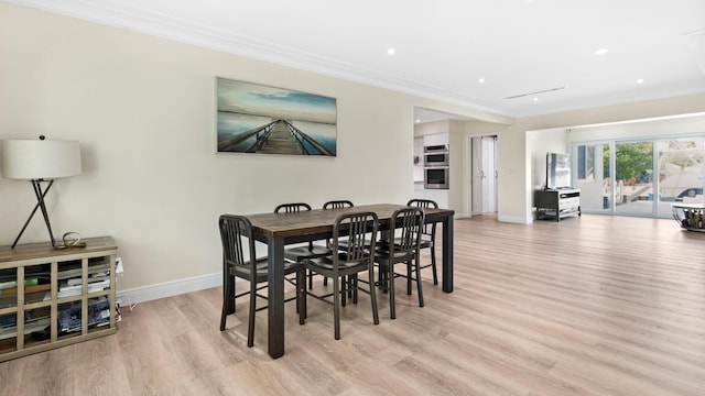 dining space with ornamental molding and light hardwood / wood-style floors