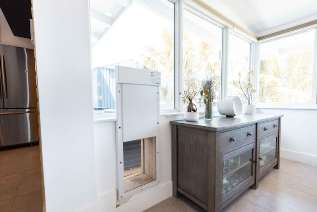 interior space with stainless steel fridge and light tile patterned flooring