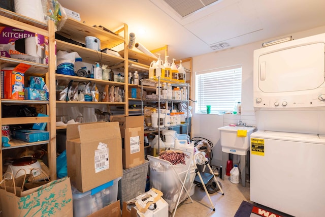 storage area featuring stacked washer and clothes dryer