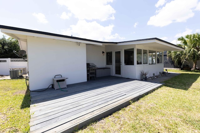 rear view of house featuring a wooden deck, central AC, and a lawn