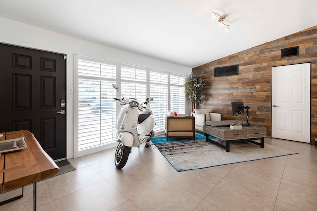 living room featuring vaulted ceiling, light tile patterned flooring, and wooden walls